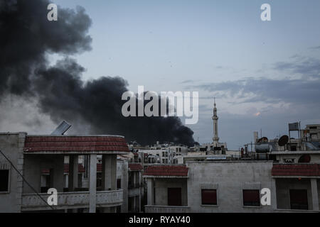 Idlib, Syria. 13th Mar, 2019. Thick smoke rises from buildings after airstrikes that believed to be mounted by Russian warplanes on residential areas in the city centre of Idlib. The Syrian White Helmets volunteer rescue group, which works only in rebel-held areas, said two women died and 19 others were injured in the strikes. Credit: Anas Alkharboutli/dpa/Alamy Live News