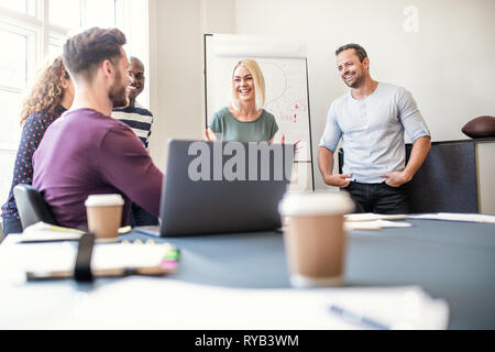 Diverse group of young designers talking together in an office after a boardroom presentation Stock Photo