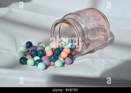 A jar of push pins on its side with pins spilling out, against a white background Stock Photo