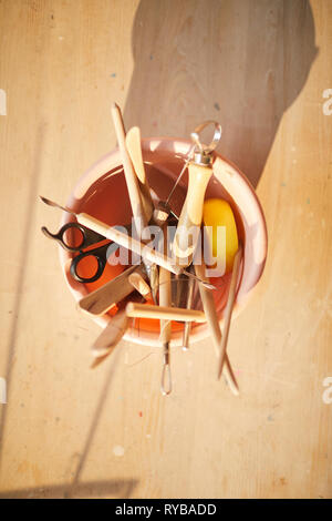 Top view at wooden pottery tools in ceramic bowl, rustic warm art background Stock Photo