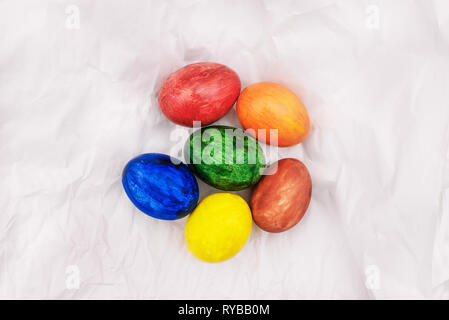 Easter eggs on white crumpled paper. Multi-colored, painted in bright colors eggs. Easter holiday Stock Photo