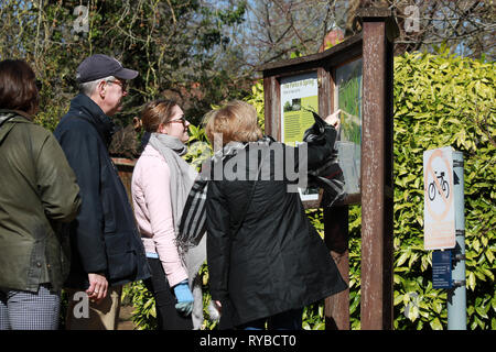 Tourists or locals looking and pointing at map of Oxford University Parks and notice board on a sunny day in winter / spring Stock Photo