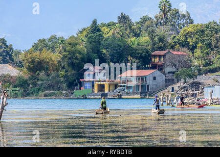 Santiago Atitlan, Lake Atitlan, Guatemala - March 8, 2019: Men paddle traditional canoes near lake shore in largest lakeside town Stock Photo