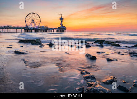 Colorful sunset on coastline, beach, pier and ferries wheel, Scheveningen, the Hague. HDR technique used, high dynamic range. Stock Photo