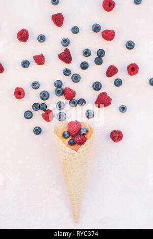 Creative Summer concept composition flat lay top view sweet fresh red raspberries blueberries ice cream waffle cone pink background copy space Templat Stock Photo