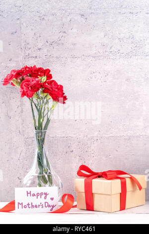 May mothers day handmade giftbox wishes photography - Beautiful blooming carnations with red ribbon box isolated on fair-faced gray background desk, c Stock Photo