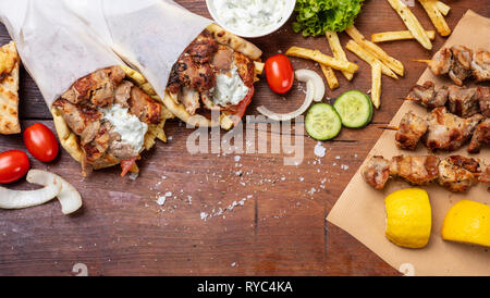 Gyro pita, shawarma, souvlaki. Traditional turkish, greek meat food. Two pita bread wraps and meat skewers on wooden table, copy space, top view Stock Photo
