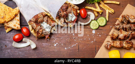 Gyro pita, shawarma, souvlaki. Traditional turkish, greek meat food. Two pita bread wraps and meat skewers on wooden table, banner Stock Photo