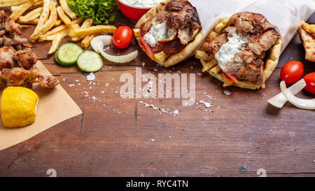 Gyro pita, shawarma, souvlaki. Traditional turkish, greek meat food. Two pita bread wraps and meat skewers on wooden table, copy space Stock Photo