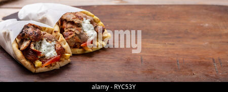 Gyro pita, shawarma, take away, street food. Two pita bread wraps with meat, traditional greek turkish food on wooden table, banner Stock Photo