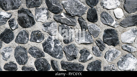 horizontal detail of a rock wall background made of small jagged granite stones Stock Photo