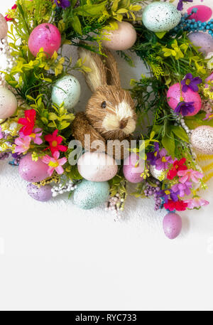 a colorful easter bunny wreath with colored eggs and flowers and white copy space background Stock Photo