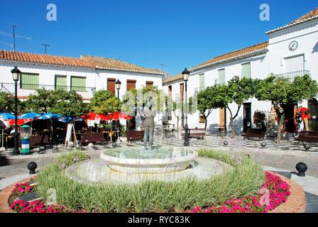Fountain in the Plaza de Espana surrounded with pretty flowers with cafes and shops to the rear, Benalmadena Pueblo, Costa del Sol, Andalusia, Spain,  Stock Photo