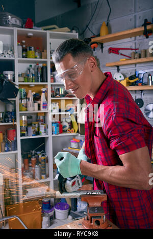 Locksmith cuts metal with a grinding machine, Mechanic power saw cuts. Stock Photo