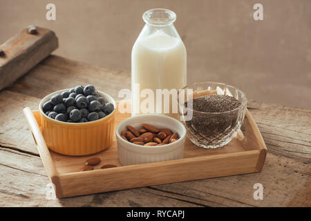Healthy vegan breakfast. Bottled milk with chia, almond, fresh fruit and berries over wooden table background, copy space. Clean eating, weight loss,  Stock Photo