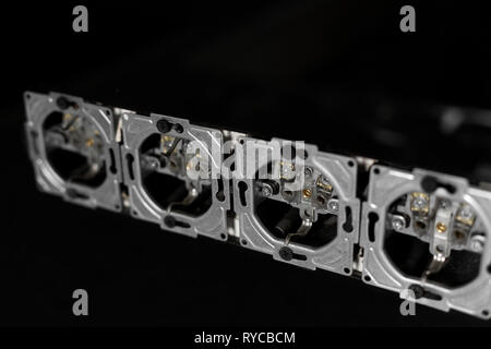 Five outlets in line, disassembled and mounted in black glass wall. Stock Photo