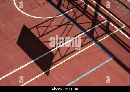 Semi-abstract view of a red basketball court with sunlight and shadow and court lines creating interesting shapes, Dubrovnik, Croatia Stock Photo