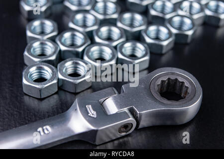 New chrome-plated key ring with latch and nut. Accessories for a mechanic on a workshop table. Dark background. Stock Photo