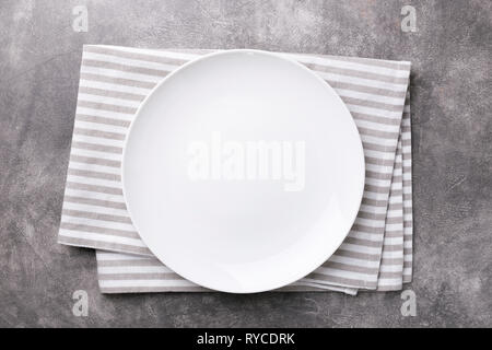 Empty plate with striped napkin on gray stone background. Top view. Stock Photo