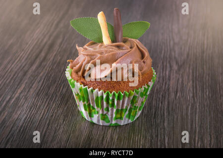 Isolated chocolate cupcake on dark wooden table background with mint leaves. Pastry muffin Stock Photo