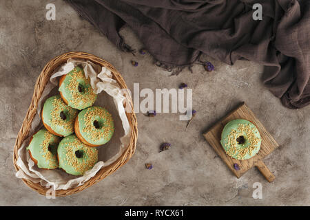 Cooking, baking and food concept - close up of glazed donuts in a wicker basket on a textured background. Still life. Stock Photo