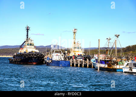 Tug boat and fishing trawlers tied up at wharf in Eden Harbour on Two Fold Bay on the New South Wales southern cost Stock Photo