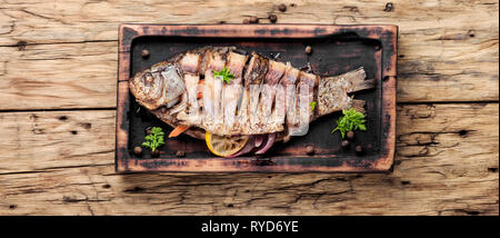 Grilled whole fish loaded with citrus and spices on rustic wooden table.Tasty baked fish Stock Photo
