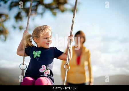 Young girl enjoys swinging on tree swing. Stock Photo