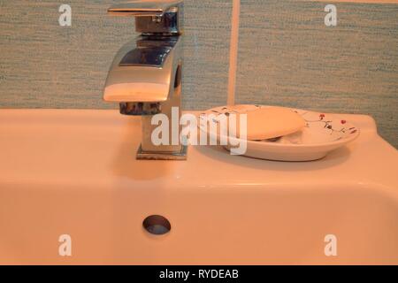 Modern faucet and classic soap dish on white basin.  Minimalist concept. Stock Photo
