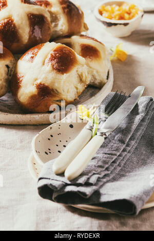 Easter table setting with plate of hot cross buns on table with linen tablecloth. Close up Stock Photo