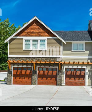 Fragment of farmer's house with three garage doors and concrete driveway Stock Photo