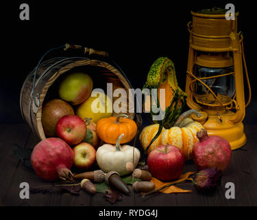 Abstract still life displaying  harvest symbols and a German gas lantern, against wooden background and decorated with colorful fall leaves Stock Photo