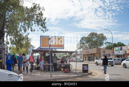 South African town street scene of pedestrians and people walking on the pavement and shopping at a roadside market stall on a busy Saturday morning Stock Photo