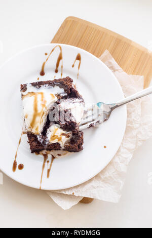 Chocolate Brownie with a scoop of vanilla ice cream mod chocolate sauce on a white plate. Top view, flat lay Stock Photo