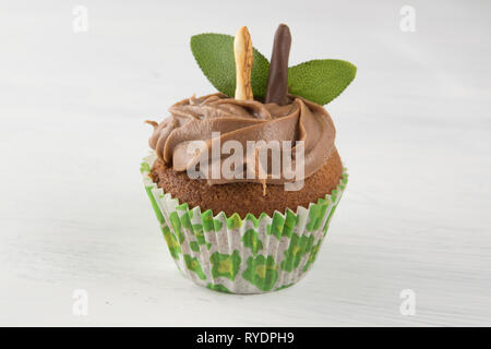 Isolated chocolate cupcake on white table background with mint leaves. Pastry muffin Stock Photo