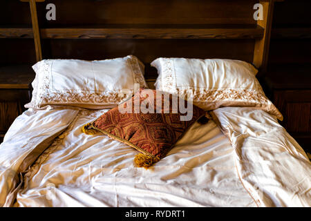 Antique vintage retro wooden queen bed in luxury room with old-fashioned decorations brown pillows in home Stock Photo