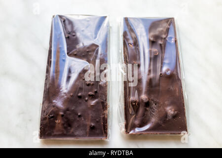 Flat top closeup of two packaged in plastic milk or dark chocolate bars with fruits and nuts hazelnuts almonds on table Stock Photo