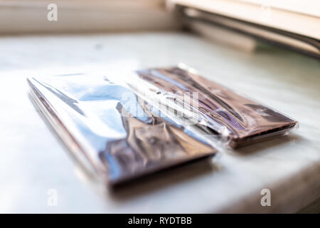 Closeup of two packaged in plastic milk or dark chocolate bars blocks with fruits and nuts hazelnuts almonds on table Stock Photo