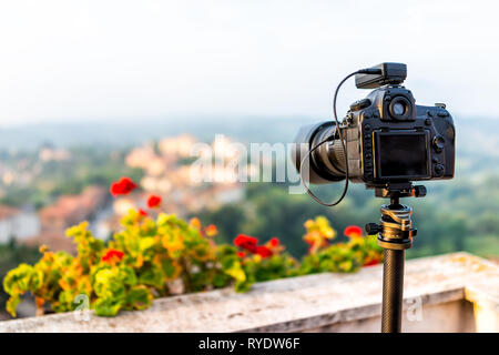 Chiusi Scalo sunset or sunrise of houses buildings in Tuscany, Italy with town cityscape and focus on dslr camera on tripod by flowers garden foregrou Stock Photo