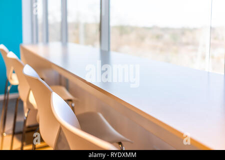 Closeup of new modern office room lunch kitchen bar in building with wooden corporate business table by glass window and many row chairs empty nobody Stock Photo