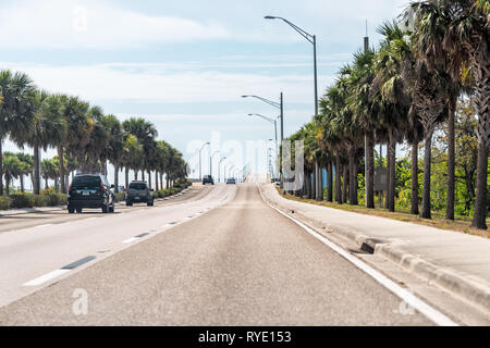 Fort Myers, USA - April 29, 2018: City town street during sunny day in Florida gulf of mexico coast with highway road and cars and palm trees lined Stock Photo