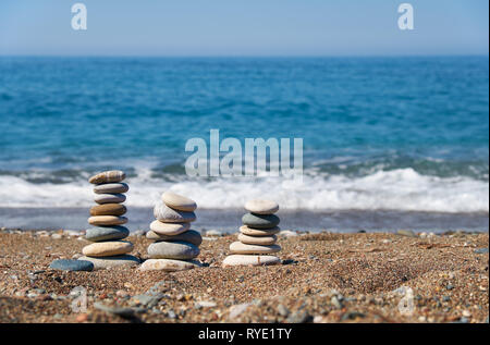 Stack of stones on Petra tou Romiou or Aphrodite Rock Beach, Cyprus. Stones pyramid on pebble beach with sea and blue sky on background. Stock Photo