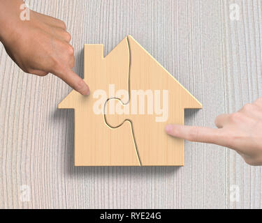 Woman and man two hands assembling wooden house shape puzzles, high angle view, on wood plank background. Stock Photo