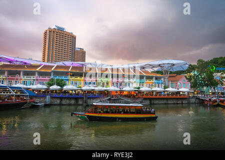 Pink sunset clouds over colourful Clarke Quay, where tourists ride boats along the Singapore river. Stock Photo