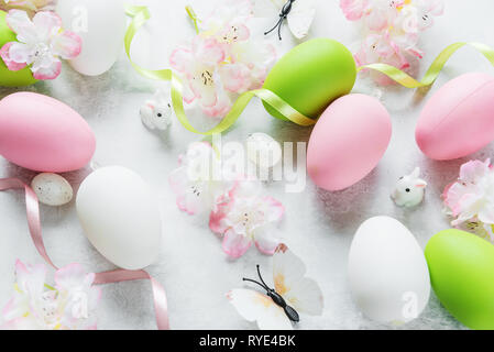 Beautiful delicate Easter composition with pink cherry flowers, multicolored Easter eggs, Easter bunny and butterfly on the stone background Stock Photo