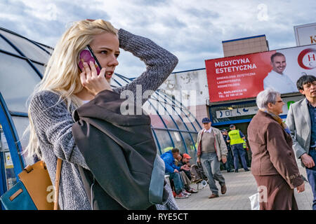 Young girl on mobile phone with arm raised over her head while talking in Warsaw, Poland Stock Photo