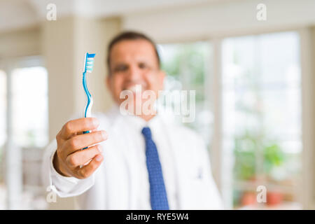 Middle age dentist man holding toothbrush and smiling Stock Photo