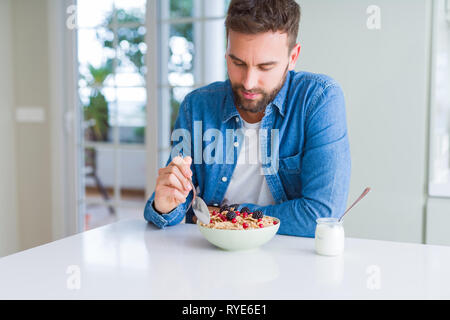 Handsome man having breakfast eating cereals at home and smiling Stock Photo