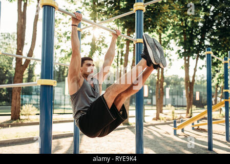 Man doing exercise on press using horizontal bar Stock Photo