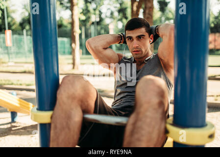Man doing exercise on press outdoor, back view Stock Photo
